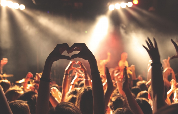 Hands in the air at a concert making heart shapes