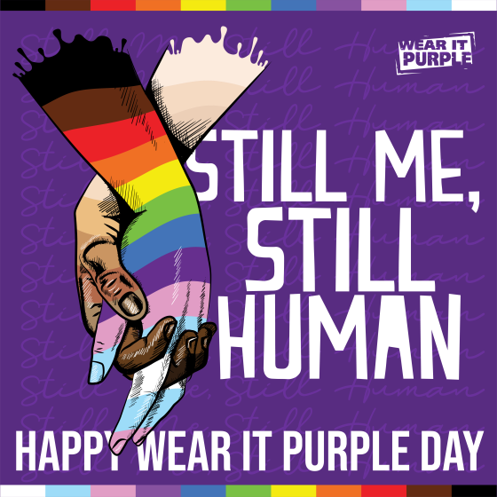 Purple background with still me, still human, happy wear it purple day written and interlocking hands