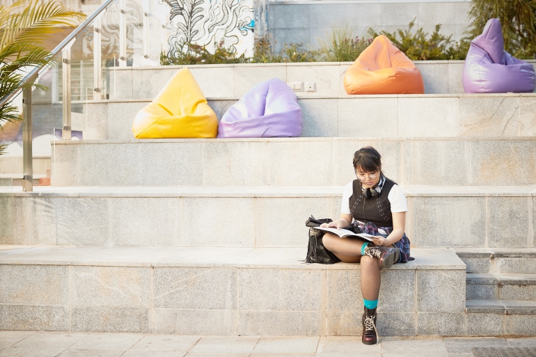 A student sat on his own on some concrete steps with coloured beanbags