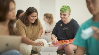 A student with bright green hair working with another student