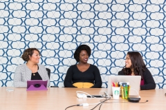 3 women sat at a table with a retro wallpaper behind