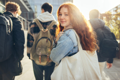 Female red hair student walking behind friends and looking at the camera