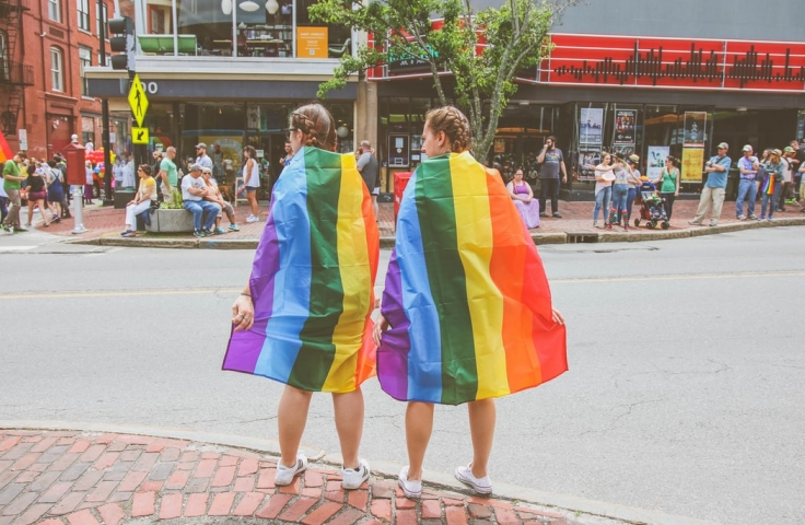 Two women wearing pride flags