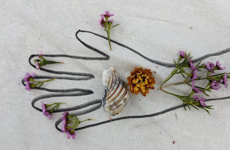 A black outline of a hand with purple flowers and a shell placed inside