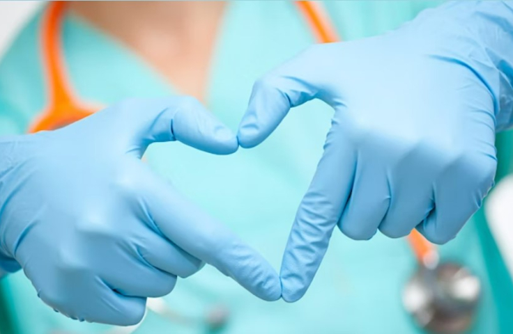 Hands in blue medical gloves making a love heart