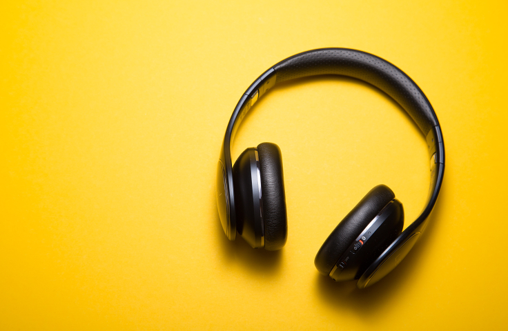 Black over ear headphones on a yellow background