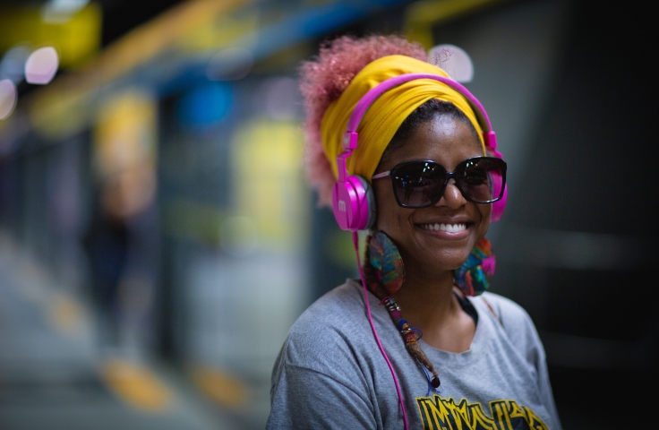 Black woman smiling with pink headphones on 