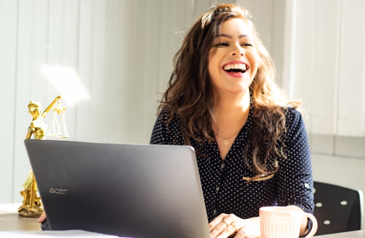 Woman at a laptop happy and smiling 